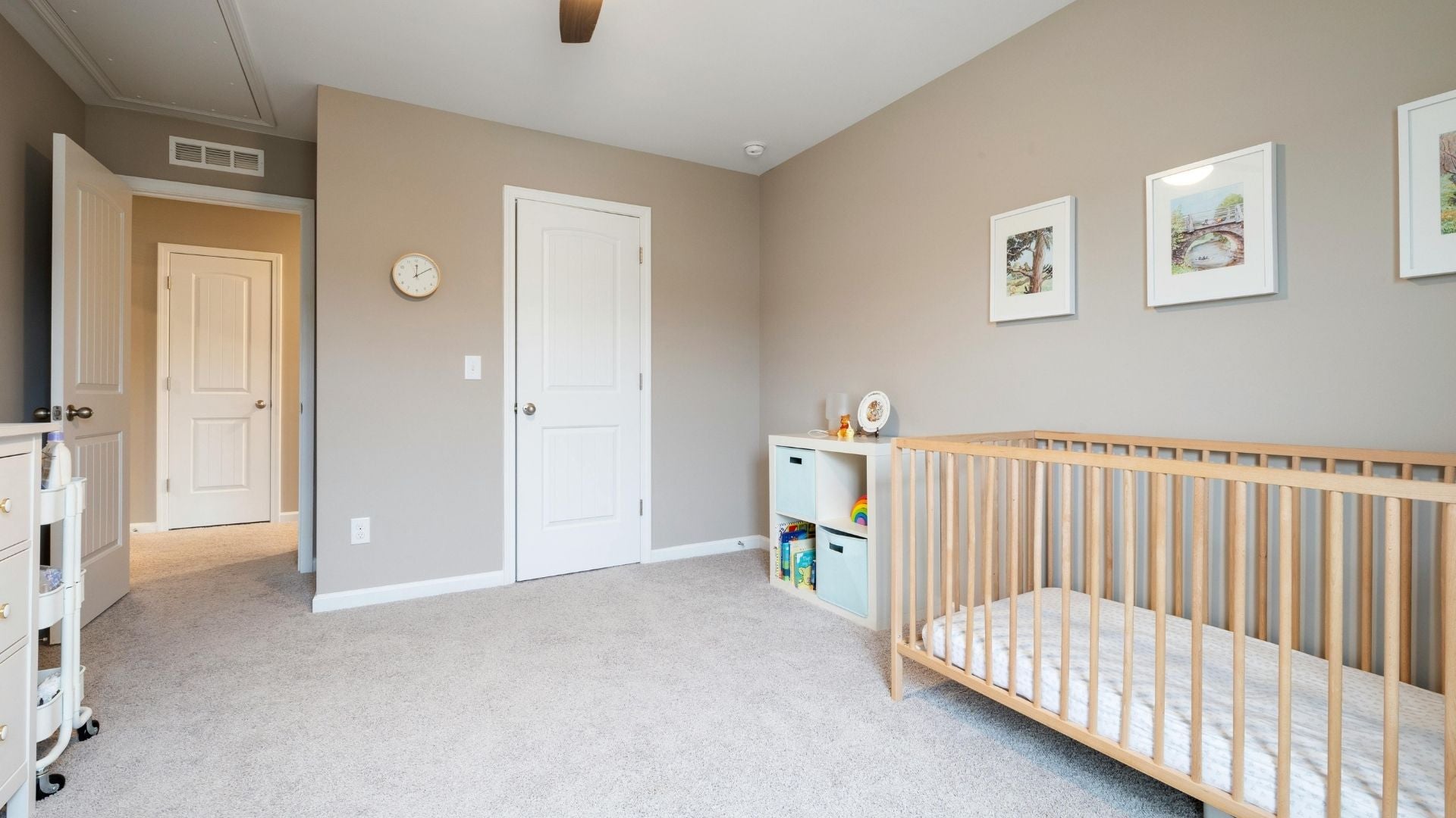 A babies room/nursery with a cot, draws and a clean beige carpet