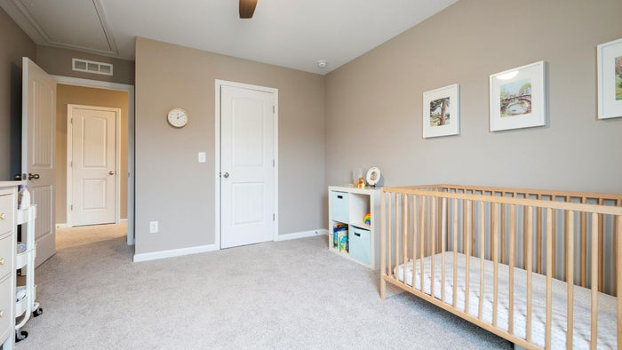 A babies room/nursery with a cot, draws and a clean beige carpet