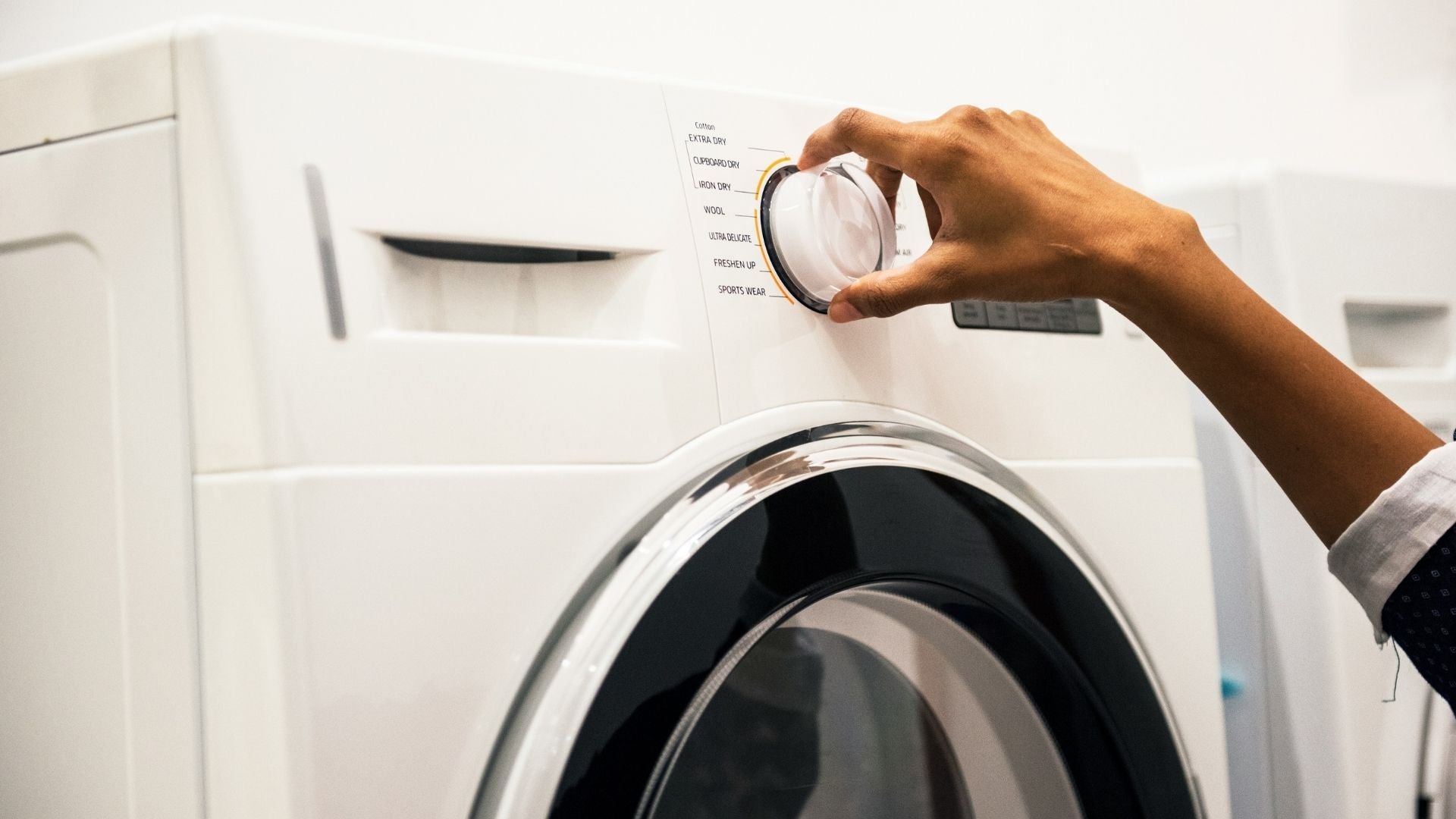 Hand on the dial of a washing machine